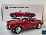 a red model of a classic car in front of a box