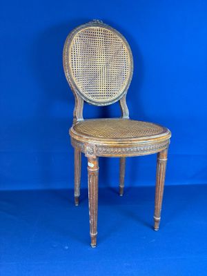 une vieille chaise en bois avec une assise en osier, sur fond bleu