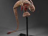 une sculpture représentant un lézard, posée sur un socle et ornée de perles rouges