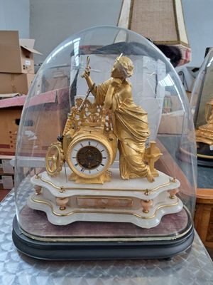 une horloge en or sous un dôme de verre sur une table