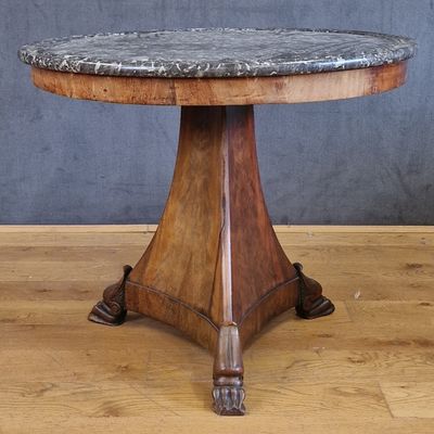 une table avec un plateau en marbre posée sur un parquet