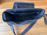 a black bag with a strap on it sitting on a wooden floor