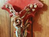 a red vase with flowers in it on a wooden wall