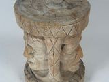 an image of a wooden stool with a carved face on top of it