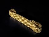a close up of a gold bracelet on a black background