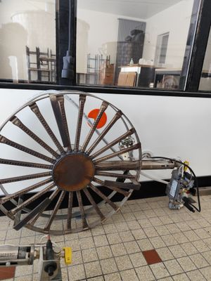 une grande roue métallique posée par terre près d'une fenêtre