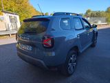 the rear end of a grey car parked in a parking lot