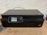 a printer sitting on top of a wooden table next to a plant
