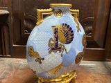a blue and gold vase sitting on top of a wooden table