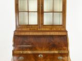 an antique wooden secretary ' s desk with glass doors and drawers