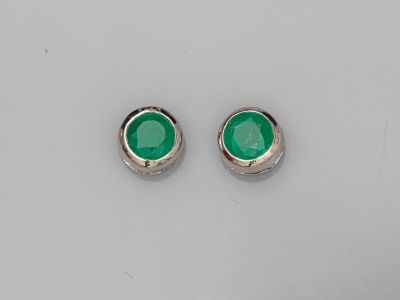 une paire de boucles d'oreilles à clous en verre vert posées sur une surface blanche