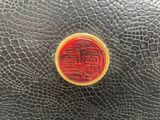 a red and gold chinese seal on a black leather surface