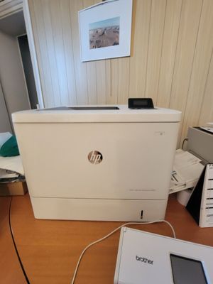 une imprimante blanche posée sur un bureau, à côté d'un ordinateur portable