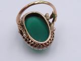 a close up of a ring with a green stone in it