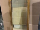 mirror with gold frame and gold leaf decoration on top of it
