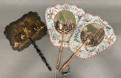 three antique hand fans with pictures of people on them on a table