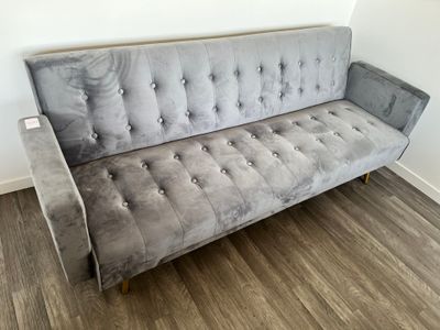 canapé en velours gris capitonné dans une pièce avec du parquet