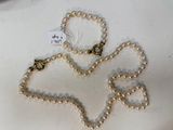 a white pearl necklace with a gold clasp on a white table