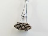 silver bell on a white surface with a silver chain around it
