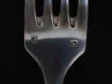 a silver fork with holes in it on a black background