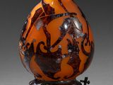 un vase orange et noir posé sur un socle en métal