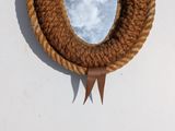 a mirror hanging on the wall with a rope around it