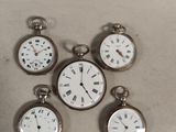 four silver pocket watches sitting on top of a table next to each other