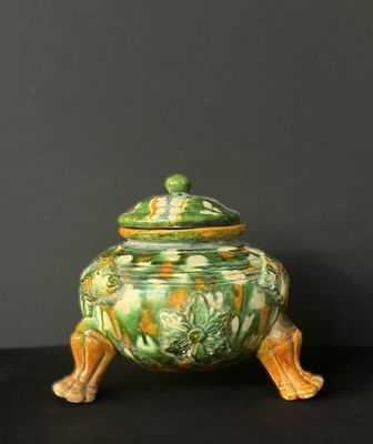 an image of a green and yellow vase with a lid on a black surface
