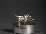 une image représentant une figurine en argent représentant un sanglier posée sur un coffret en argent