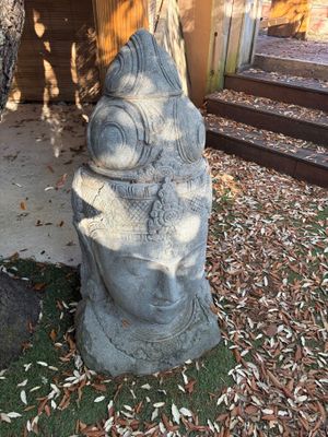 une statue en pierre représentant un visage, posée à même le sol