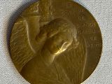 une médaille d'or sur laquelle figure le visage d'une femme, posée sur un tissu blanc
