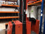 un chariot élévateur dans un entrepôt rempli de cartons et de palettes