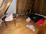 a bed and a chair in the attic of a house