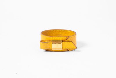 un gros plan d'un bracelet jaune sur fond blanc