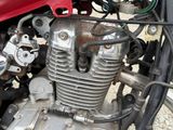 a close up of a motorcycle engine with a red car in the background