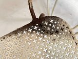 a metal basket with holes on it sitting on a table
