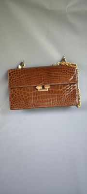 un sac à main en cuir de crocodile marron avec une chaîne dorée