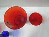 two red glasses and a blue bottle on a white table