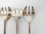 three forks that are sitting side by side on a table