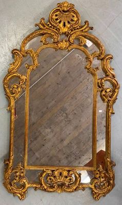 gold ornate mirror on a wall in a room with a wooden floor