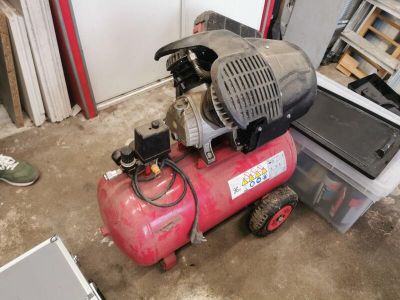 a red air compressor sitting on the floor in a garage