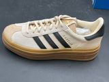 the adidas sneakers are white with black stripes and tan soles