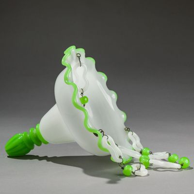 a white and green vase with green beads on it