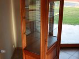 a corner cabinet with a glass door in a room