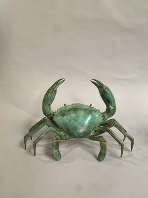 un crabe vert posé sur une surface blanche