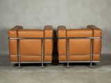 two brown leather chairs sitting next to each other in a room