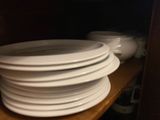 a lot of plates stacked on a shelf in the kitchen