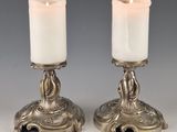 pair of silver candles with candlesticks on stands on a table