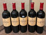 six bottles of red wine are lined up on a wooden barrel