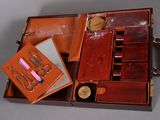 a brown case with a mirror, scissors, and other items in it